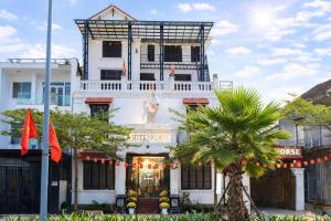 a white building with a tree in front of it at White Horse Homestay in Hue +21 photos