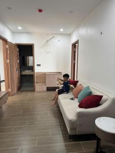 a little boy sitting on a couch in a living room at Lighthouse Apartment in Ða Gia
