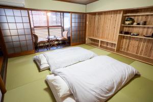 a room with two beds and a table in it at 尾道つばめ堂 Onomichi Tsubamedo in Onomichi