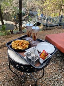 a tray of food on a table with two drinks at Treetop Glamps in Mussoorie +48 photos