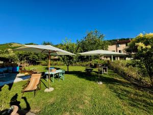 a yard with two umbrellas and a table and chairs at Ca' di Romagna B&B in Civitella di Romagna +10 photos