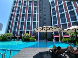 a swimming pool with chairs and umbrellas in front of a building at Inap II, Suterabay By Ayuhouz in Kota Kinabalu