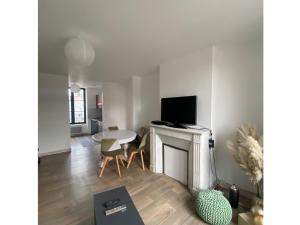 a living room with a table and a tv on a fireplace at chez Alain et Sylvie in Braine