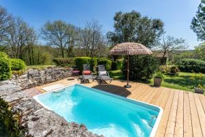 a swimming pool with two chairs and an umbrella at La chambre d Adèle in Masquières