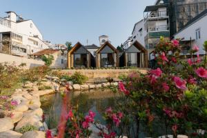 a house with a pond in front of some flowers at Zenora Homestay in Khu Chi Lăng