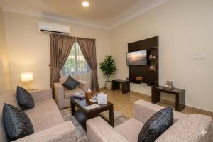 a living room with two couches and a tv at Hadiqat Lina Serviced Apartments Dammam in Dammam