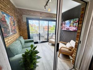 a living room with two green chairs and a brick wall at Centurion La Creme Apartments in Centurion