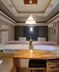 a bedroom with two beds and a wooden table at Hiddenhill Bulkuksa Hotel in Gyeongju
