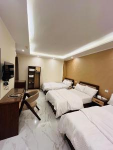 a hotel room with three beds and a desk at Pr Pyramids Inn in Cairo