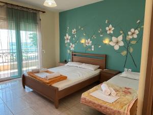 two beds in a bedroom with flowers on the wall at Studios-Heaven in Chrysi Ammoudia +3 photos