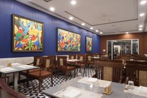 a restaurant with tables and chairs and paintings on the wall at Mayfair Waves in Puri