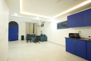 a kitchen and a living room with blue cabinets at Greek House By Housiify in Gurgaon