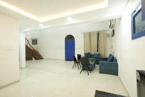 a living room with a blue door and chairs at Greek House By Housiify in Gurgaon