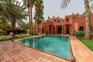 a swimming pool in front of a house with palm trees at Dar Mardan in El Aggada