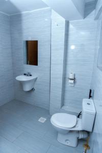 a white bathroom with a toilet and a sink at Arise Sunshine Hotel in Narok