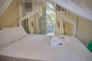 two towels sitting on a bed with a window at Razz Homes in Diani Beach