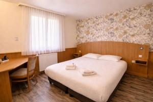 a hotel room with a bed and a desk and a table at Logis Hôtel Restaurant Les Fontaines in Lanvollon