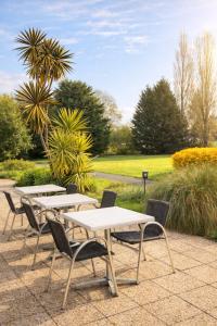 a row of tables and chairs in a park at Logis Hôtel Restaurant Les Fontaines in Lanvollon