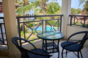 a balcony with a glass table and chairs and a pool at Razz Homes in Diani Beach