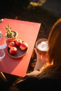 a woman holding a doughnut in front of a plate of fruit at Landpalais Goyenhof - Deluxe Suites & Breakfast in Schenna