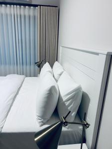 a bedroom with a white bed with white pillows at Willow Villa Apartments, at The Fig in Gaborone +12 photos