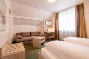 a hotel room with two beds and a couch at Hotel Zur Traube in Velbert