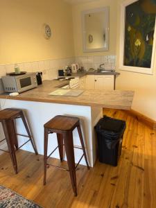 a kitchen with a counter and two stools at Waterfront Apartment in Dingle