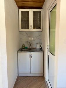 a kitchen with white cabinets and a sink at Verica in Dobrota +6 photos