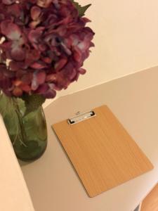 a wooden clipboard next to a vase of flowers at Grazerhof in Graz