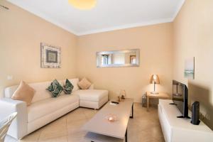 a living room with a white couch and a tv at Almancil Park Apartment in Almancil