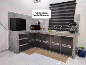 a kitchen with a counter with a sink and a tv at Homestay HABI Residence in Kepala Batas