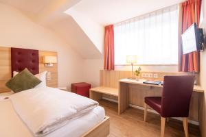 a bedroom with a bed and a desk with a computer at Hotel Zur Traube in Velbert