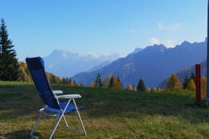a blue chair sitting in a field with mountains in the background at Valles Vacanze - ski in & ski out in Falcade