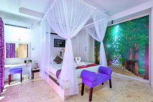a bedroom with a canopy bed and a purple chair at Lavender Private Villa Kuta Bali in Kuta