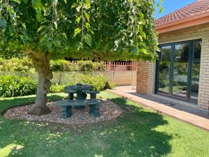 a picnic table under a tree in a yard at Peach Blossom Guesthouse in Welkom +10 photos