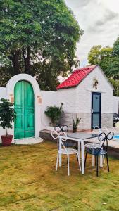 a table and chairs in a yard with a green door at Asmi by Beal's Farm in Jaipur