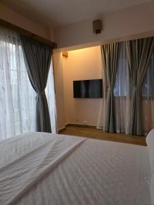 ein Schlafzimmer mit Bett und Flachbildfernseher in der Unterkunft The CRADLE in Daressalam