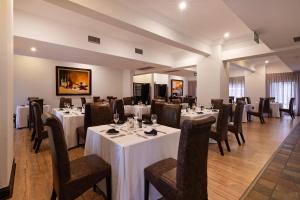a dining room with white tables and chairs at Basdenwood Hotel in Centurion