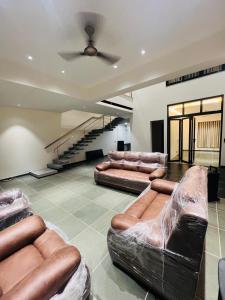 a living room with leather couches and a staircase at Weekend villa in Rajkot +1 photo