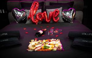 a bed with a love sign and a plate of food at L'Eclipse - Exceptional SPA Suite, sauna and hammam in Douai