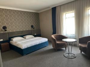 a hotel room with a bed and a chair and a table at Khan Boutique Hotel in Almaty