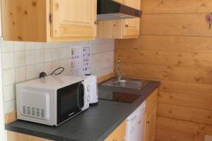a kitchen with a microwave and a sink at Valles Vacanze - ski in & ski out in Falcade