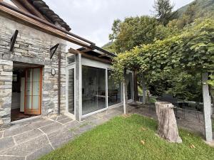 a stone house with a glass door and a tree at Romantic Ticino Rustici in Gordola