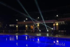 a swimming pool at night with tables and chairs at Brevant Pool Club and Resort in El Salvador