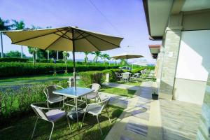a patio with tables and chairs and an umbrella at Brevant Pool Club and Resort in El Salvador