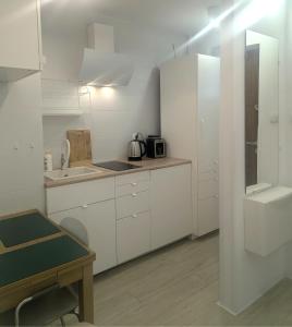 a kitchen with white cabinets and a table and a sink at Smart Centrum in Konin