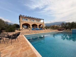 a large swimming pool with chairs and a building at Pantazi Beach House in Kotrónion