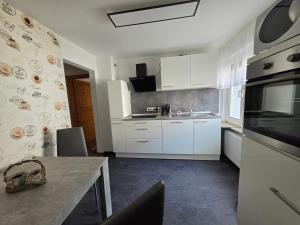 a kitchen with white cabinets and a table and a sink at Haus Perla in Saarburg