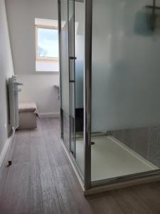 a glass shower door in a room with a window at LES CANAILLOUS 4 clos la fossette Asnelles in Asnelles