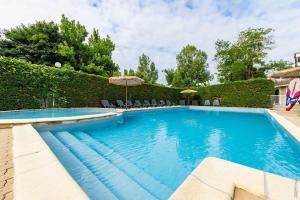 a swimming pool with chairs and an umbrella at Chalet Confort 49 in Rivières